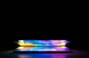 An image of an almost closed laptop with illuminating light coming from the screen.