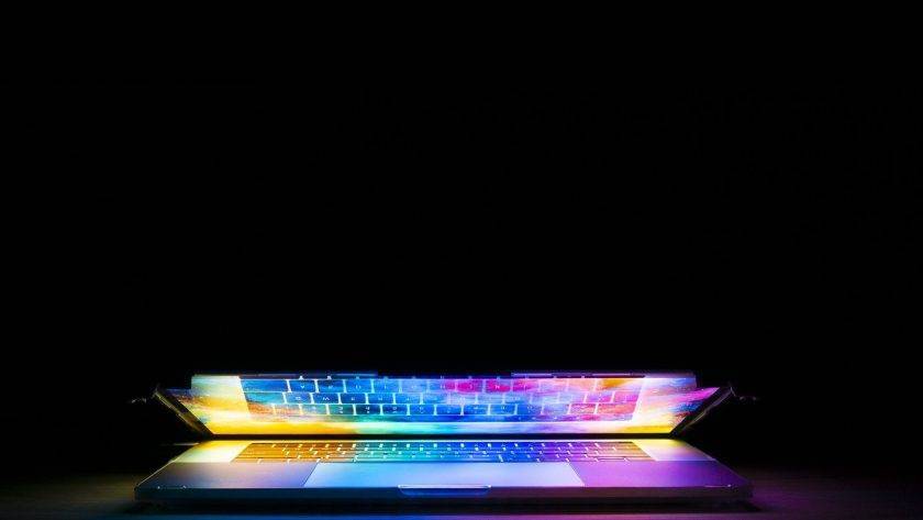 An image of an almost closed laptop with illuminating light coming from the screen.