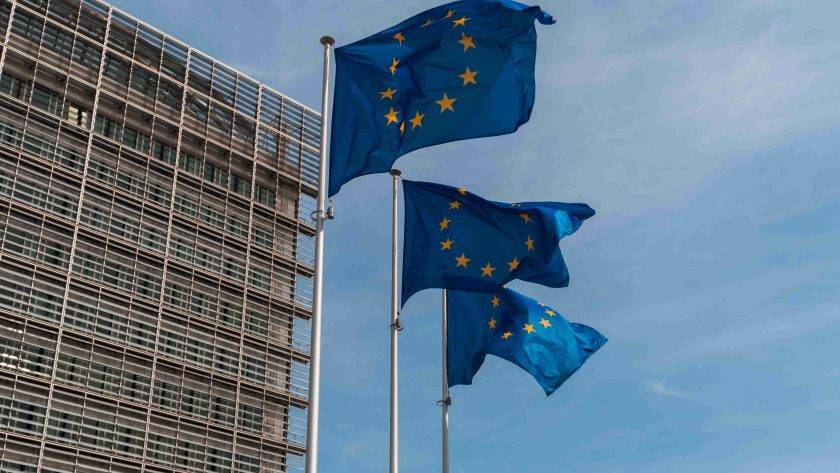 A picture of three EU flags in the wind.